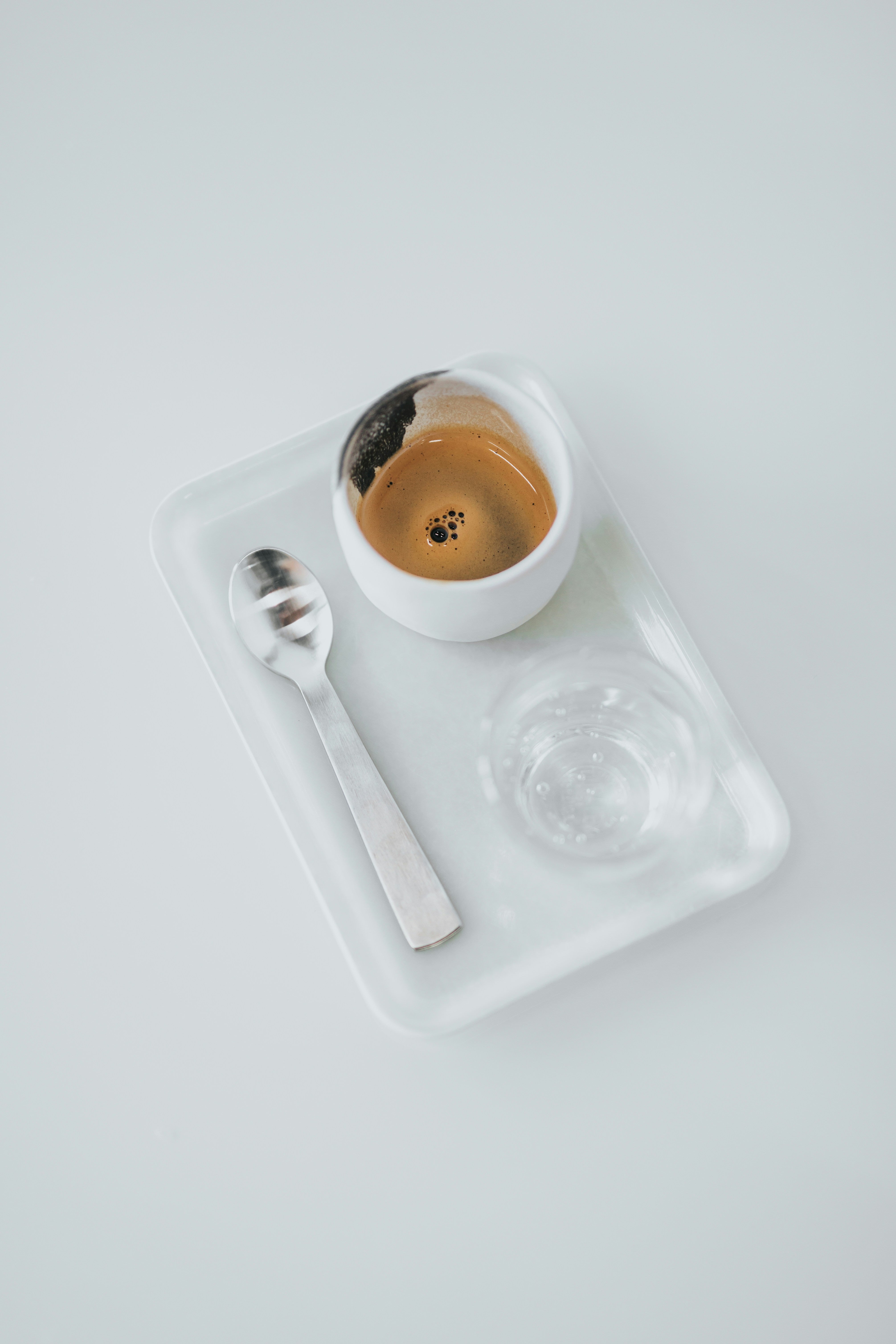 shot of espresso next to spoon and glass of water