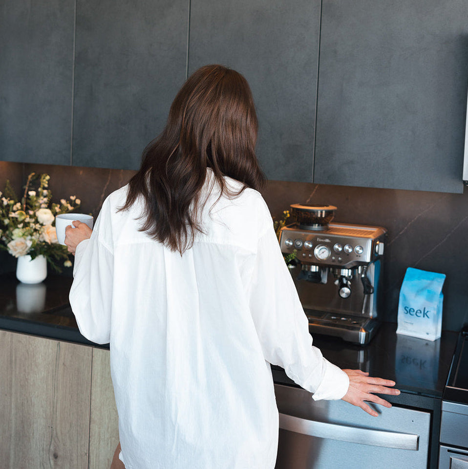 Woman in a kitchen preparing coffee using a coffee machine.