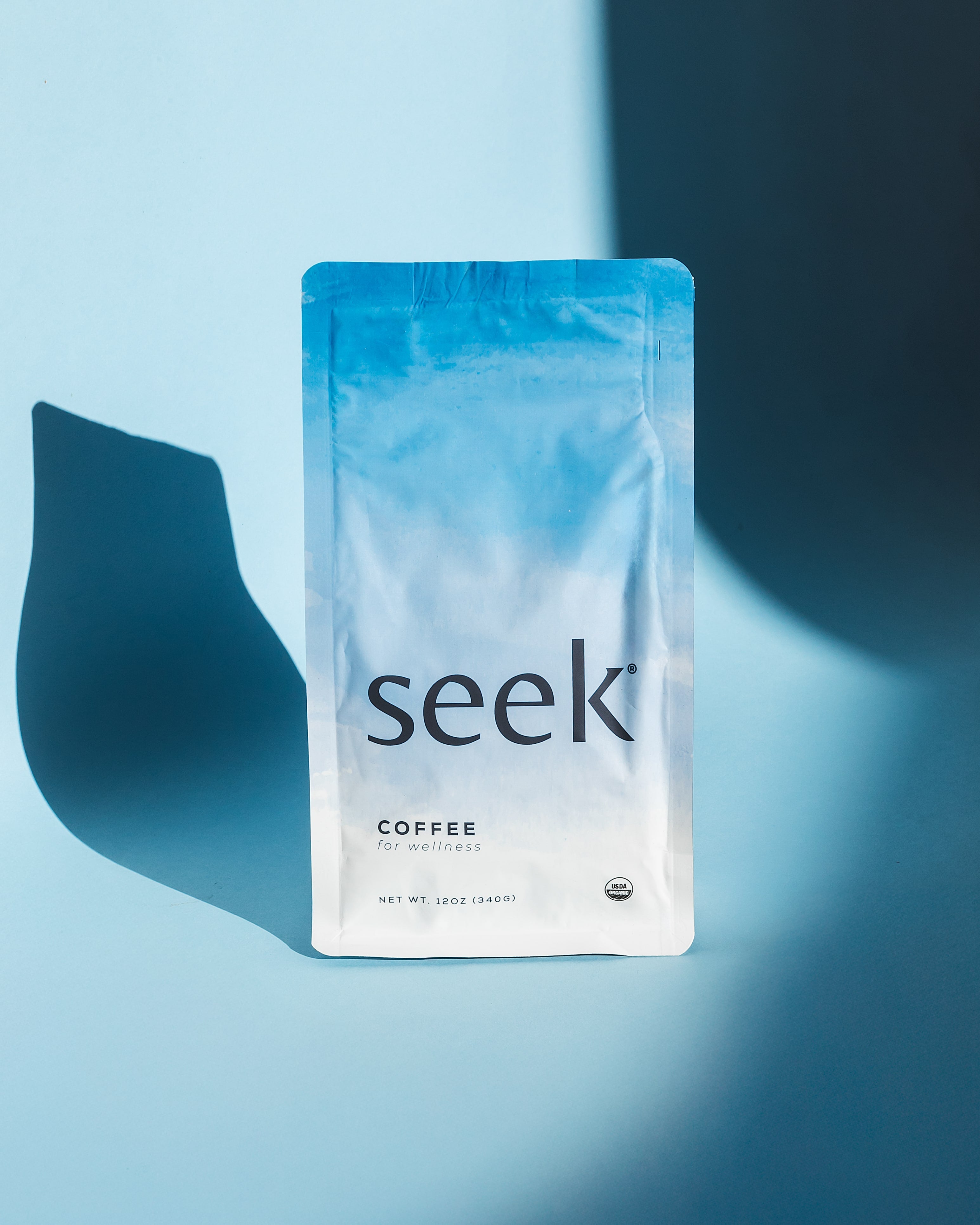 Seek® Coffee 12oz bag & Espresso labeled 'Coffee for wellness' with a minimalist, sky-blue design on a clean blue background. Promoting 100% organic, non-GMO, stomach-friendly, low-acid beans that are mold and mycotoxin-free, as well as low in histamines, Seek® Coffee is crafted for those seeking a clean, health-focused coffee experience.