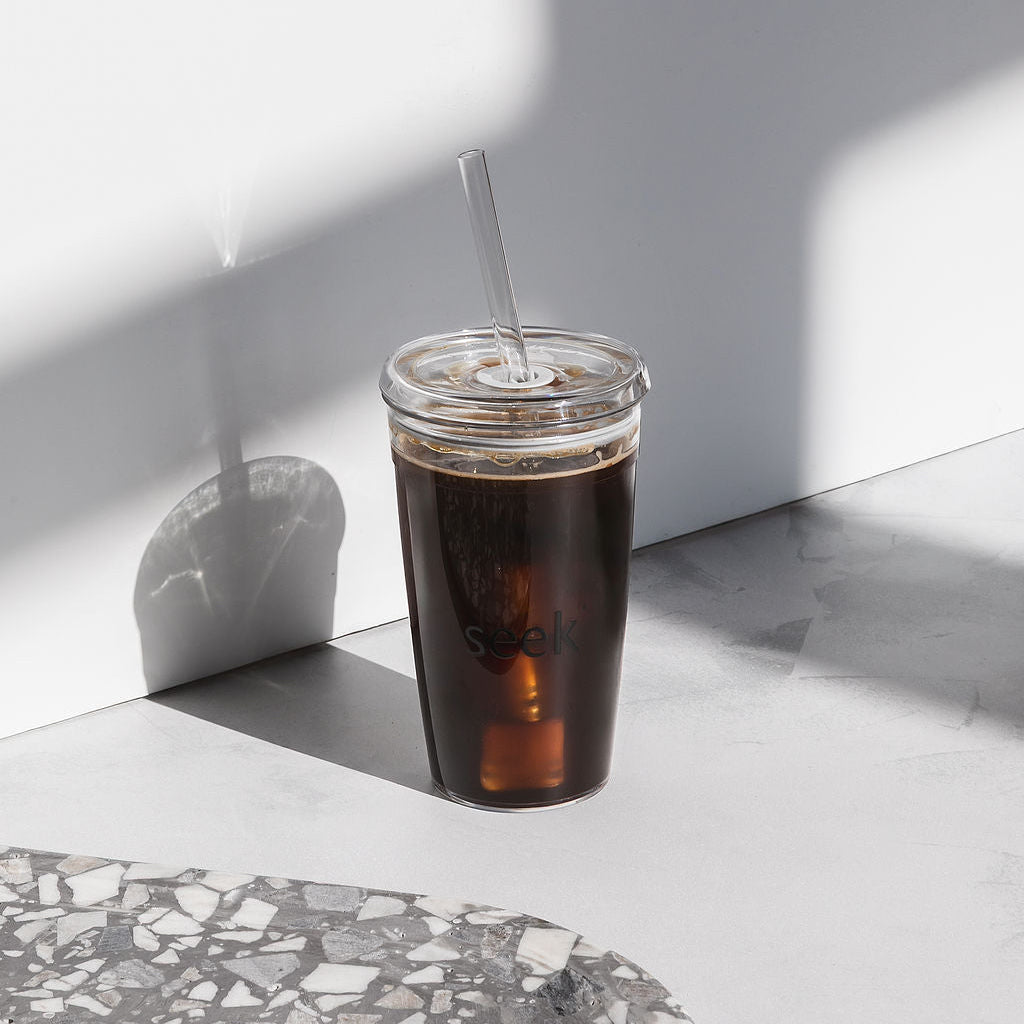 Cold brew coffee in a glass with a straw on a marble surface