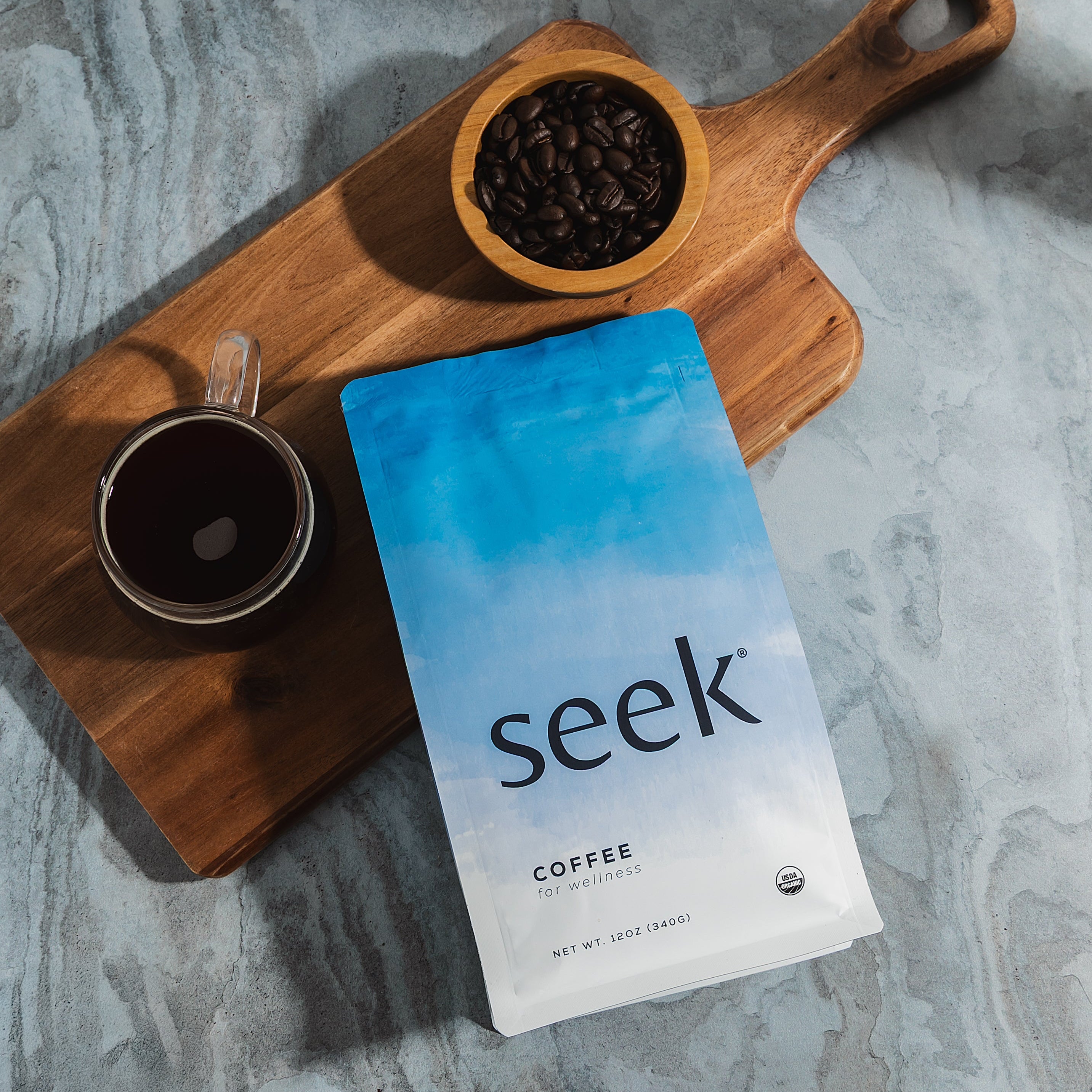 Coffee package labeled 'seek' with a cup of coffee and wooden bowl on a marble surface