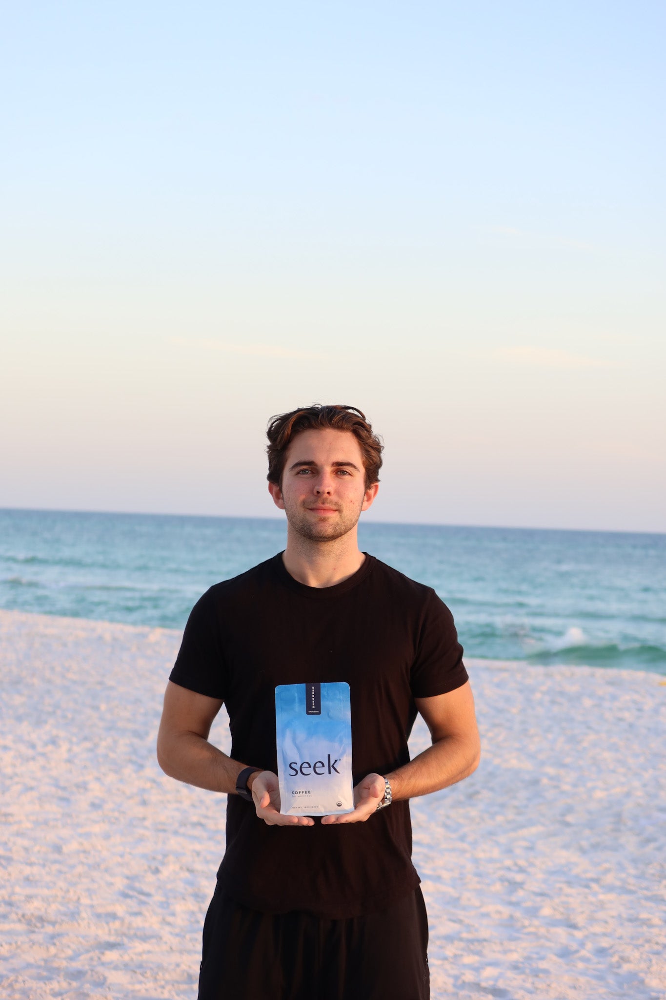 Co-founder Will holding a bag of Seek® organic mold and mycotoxin for coffee on the beach